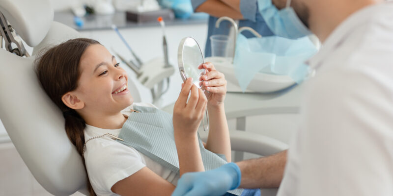 young girl in a dental chair, smiling as she undergoes a routine dental procedure