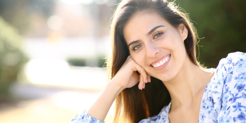 Beautiful woman with white smile looks at you in a park in Allen Park, MI